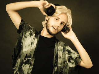 Blonde man singing in studio wearing headphones