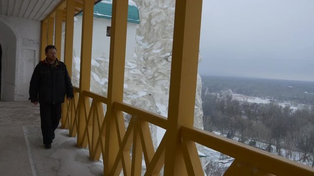 Structures on Upper Tier of Chalk Mountains Holy Mountains Lavra Gate Cave Monastery in Winter Landscape Cloudy Snowy Day Man is Walking by Balcony