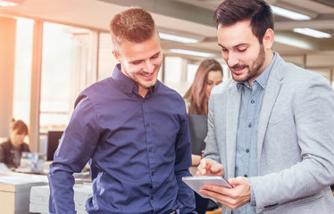 Businessmen working together on a digital tablet.