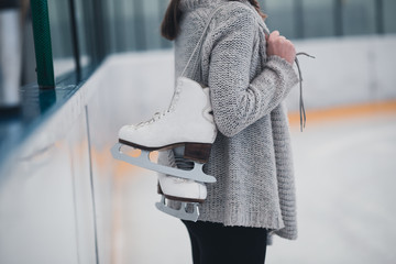 Woman at ice-skating rink holding skates. © hedgehog94