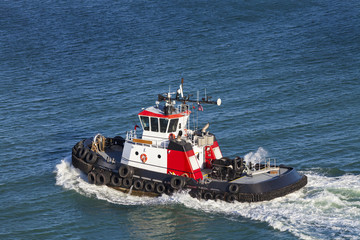 Red and White Tug Boat on the open ocean from above.