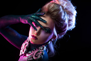 Young attractive blonde girl in bright art-makeup, in purple tones. Rhinestones and glitter body painting.