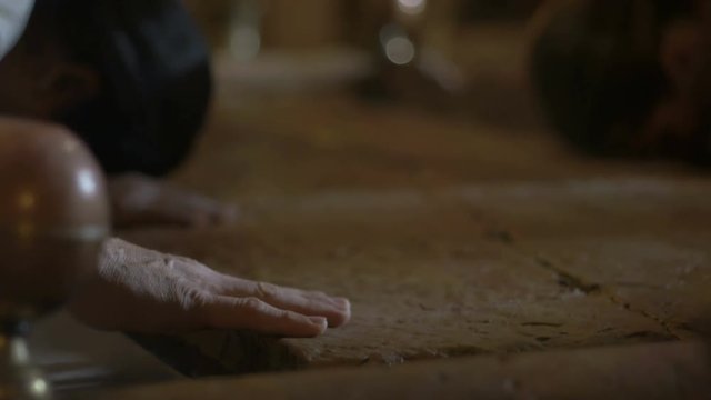 Close up of pilgrims hands at the Stone of Anointing in the Church of the Holy Sepulcher in Jerusalem.