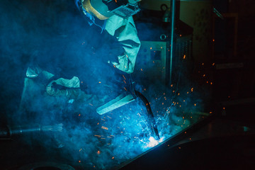 Welder of Metal Welding with sparks and smoke in steel industry