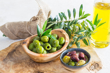 Green, mixed olives and olive oil/green olives in olive wood bowl and mixed olives and in the bowl.  