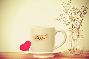 Coffee cup mug with red heart shapeand happy word tag on wooden