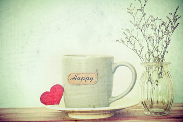 Coffee cup mug with red heart shapeand happy word tag on wooden