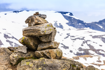 Fototapeta na wymiar Stone stack and snowy mountain tops, Dalsnibba Norway
