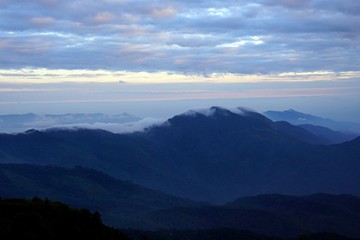 Naklejka na ściany i meble Mountain landscape with wave of fog and dark cloudy sky on the t