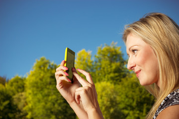Woman sitting in park, using phone taking pictures