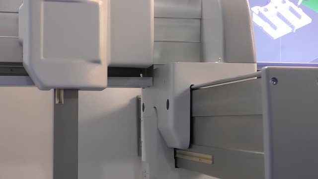 CNC automated precision 3 axis machine working, part of computer screen in the background, abstract modern technology machinery