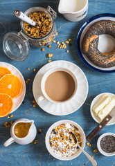 Obraz na płótnie Canvas Yogurt, pumpkin granola, bagel, butter on a blue table. Breakfast set. Top view. Flat lay