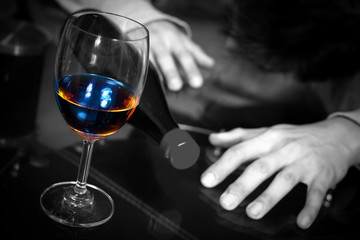 drunk and lonely asian man with wine glass and whiskey bottle, focus on glass