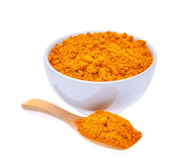 dry turmeric powder in white bowl and wooden spoon isolated on w