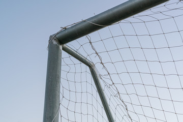 Corner of football goal. Triangle with Net of goal in football (soccer) field at evening time - soccer goal net close up.
