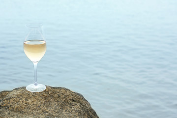 Glass of wine on rock on sea background