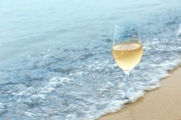 Glass of wine on sea shore, closeup
