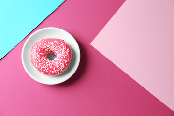 Plate with delicious donut on colorful background