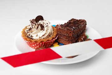 Dieting concept. Plate with delicious sweets under forbidding tape on white background