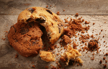 Tasty cookies with chocolate chips and crumbs on wooden background