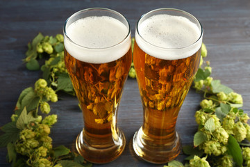 Glasses with beer and fresh hop on wooden background