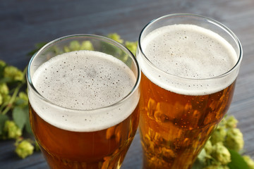 Glasses with beer and fresh hop on wooden background