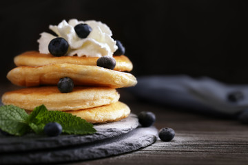 Tasty pancakes with blueberry on cutting board