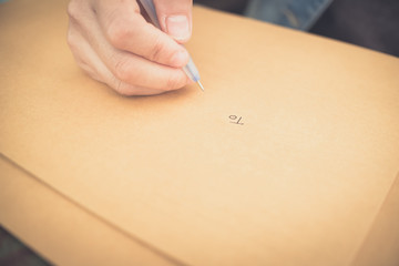 soft focus hands of a young woman as she is writing letter and notepad Or something on a wooden table .
