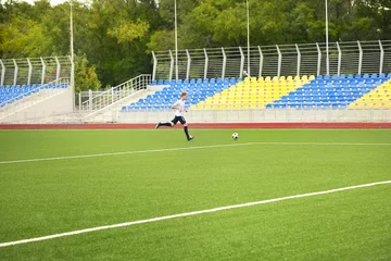 Fotobehang Voetbal Boy playing football at stadium