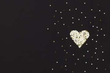 Small golden heart  made of little stars on black background. Christmas concept