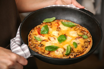 Woman holding freshly baked pizza in a pan