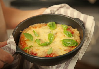 Woman holding freshly baked pizza in a pan