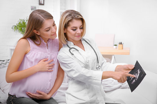 Gynecology consultation. Doctor showing pregnant woman ultrasound picture