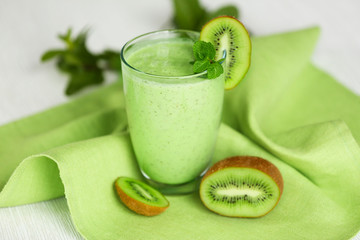 Glass of kiwi smoothie on green napkin