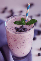 Glass of blueberry smoothie with mint on napkin