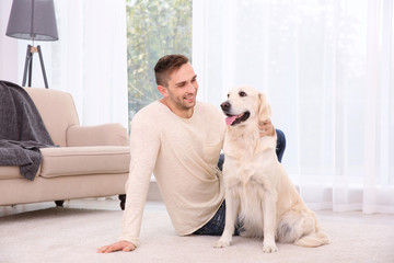 Handsome man with dog sitting on carpet at home