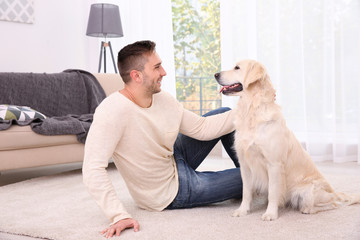 Handsome man with dog sitting on carpet at home