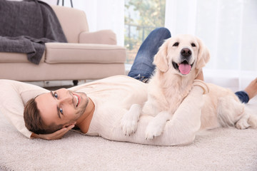 Handsome man with dog  lying on carpet at modern room interior