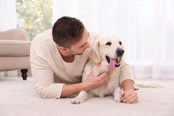 Handsome man with dog  lying on carpet at modern room interior