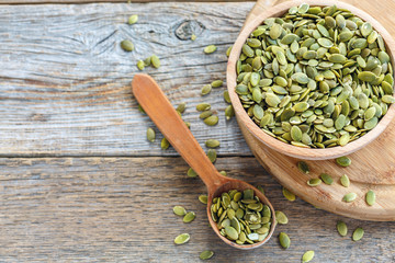 Bowl with pumpkin seeds and a wooden spoon.