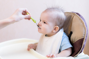 Mother gives baby food from a spoon