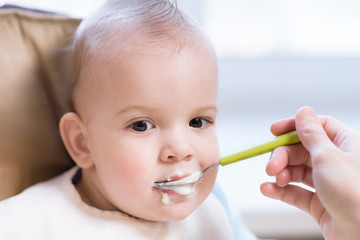 Mother gives baby food from a spoon