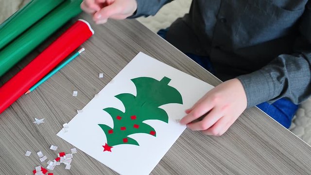 Boy making Christmas card from self-adhesive papers