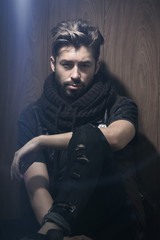 Portrait of young handsome fashionable man against wooden wall.