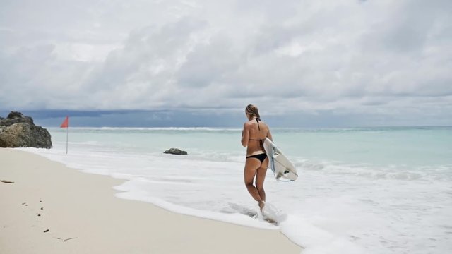 Slowmotion footage of a surf girl walking at a beautiful beach on Bali, Indonesia.