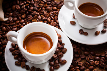 Fototapety  Dwie filiżanki espresso z dużą ilością ziaren kawy na drewnianym stole