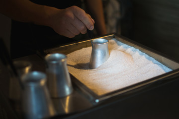 Fototapeta na wymiar Process of preparation coffee in hot sand. Hands close up