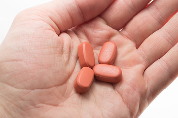 Close up of red pills in hand on white background