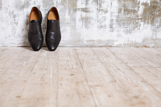Black man's shoes against a wall in retro interior.