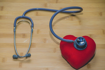 Stethoscope and red heart on wood